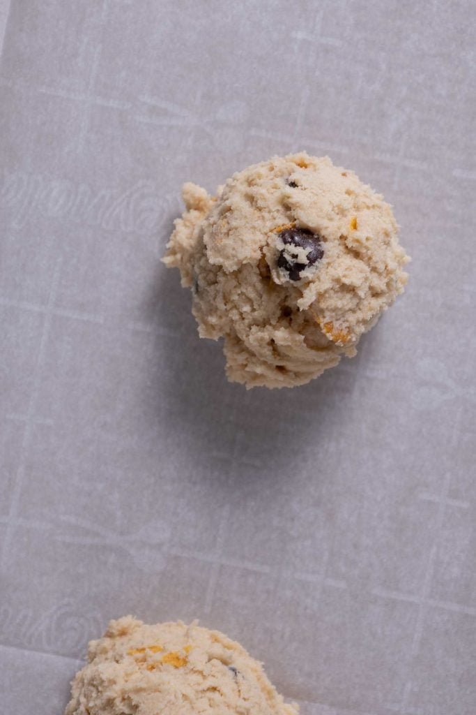 Close up of scooped cookie dough on parchment paper