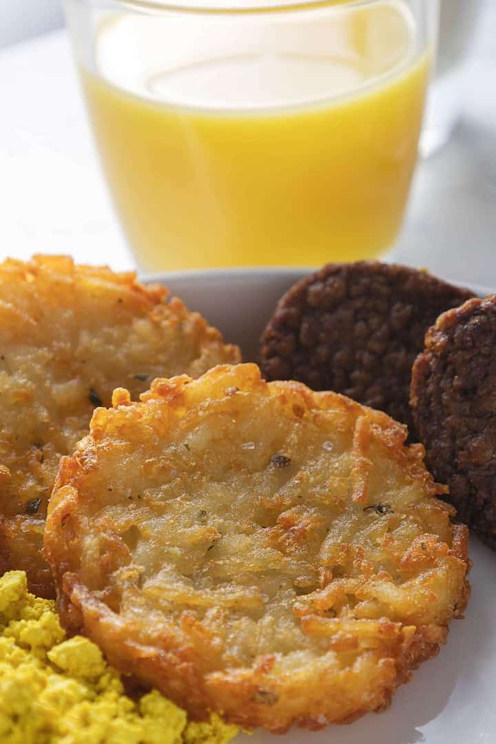 Cooked vegan crispy hash brown patties on a breakfast plate