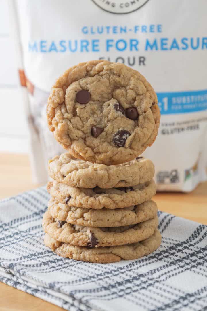 A stack of gluten free vegan chocolate chip cookies in front of a bag of gluten free flour