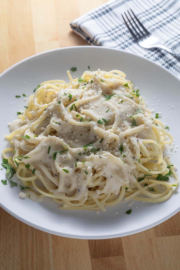 Vegan Alfredo sauce no cashews on pasta with additional plant based Parmesan sprinkles and parsley