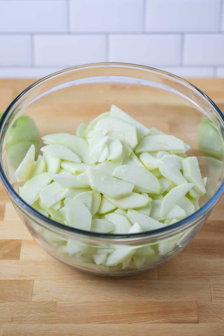 Peeled, cored, and sliced apples tossed in lemon juice for the vegan apple pie recipe 