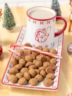 Vegan Holiday Cookies on a holiday serving plate with a mug of hot cocoa and a candy cane.