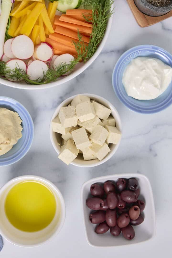 A dish of cubed tofu feta served with other Mediterranean appetizers